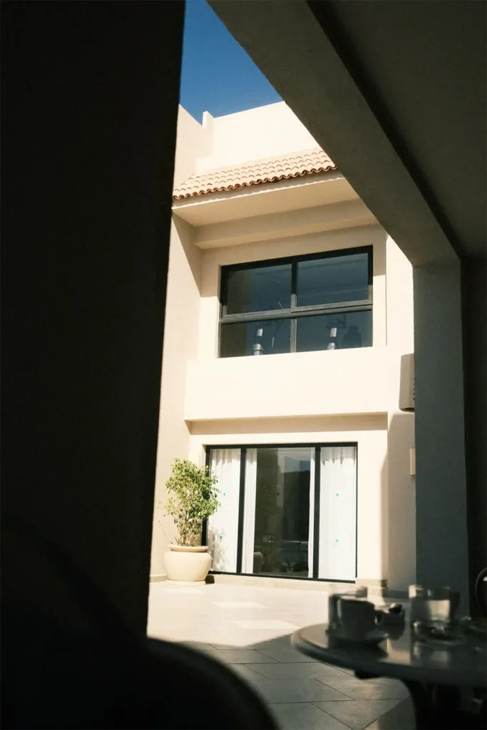 chassis aluminium noir et baie coulissante sur facade blanche cour interieure