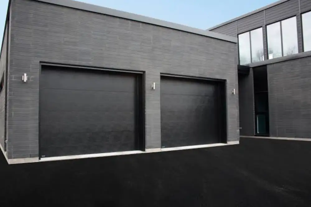 deux portes de garage sectionnelles noires sur facade brique contemporaine